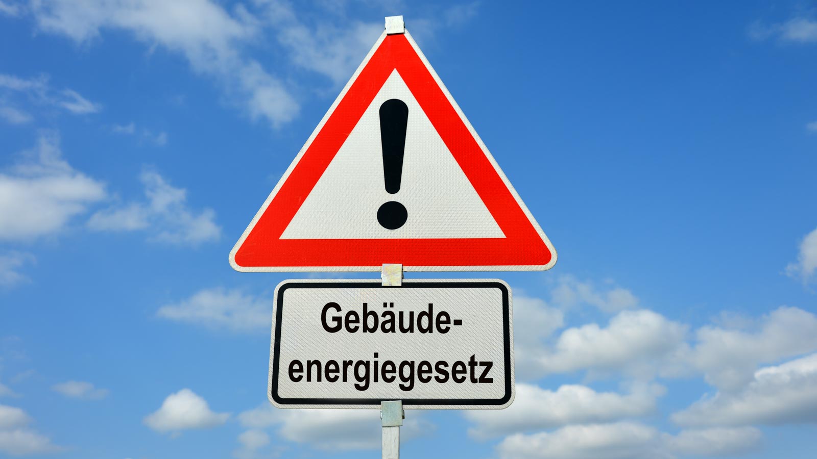 Achtung-Straßenschild, darunter Schild mit der Aufschrift Gebäudeenergiegesetz 