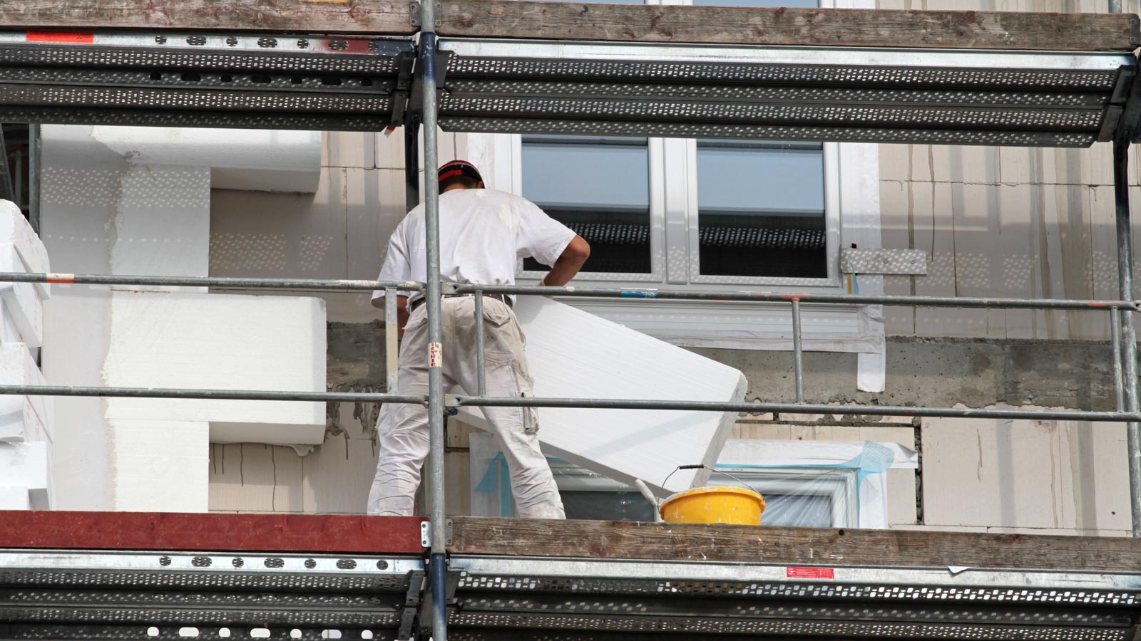 Maler dämmt eine Hausfassade mit Stryoporplatte