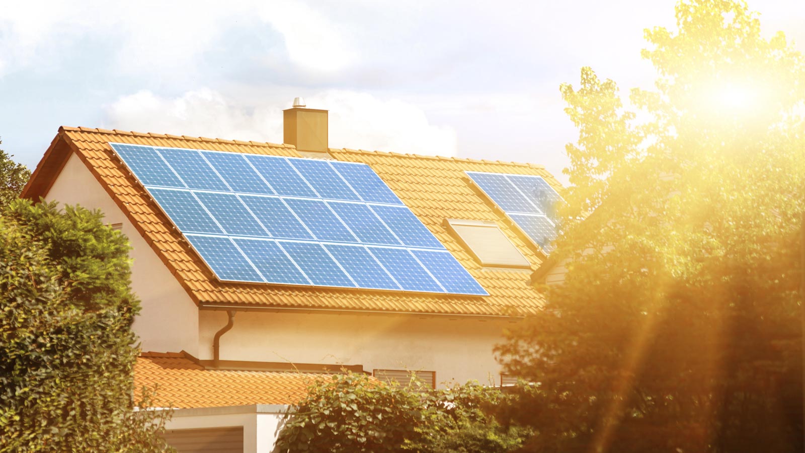 Einfamilienhaus in der Sonne mit Solarpanels auf dem Dach
