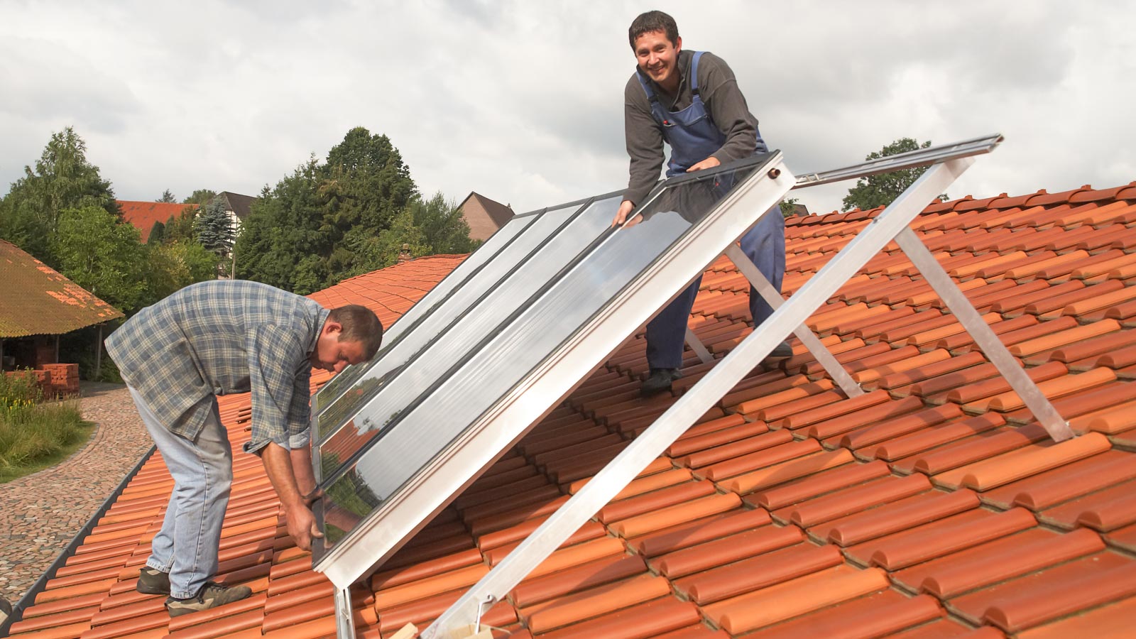 Zwei Handwerker installieren Solarpanele auf einem Hausdach
