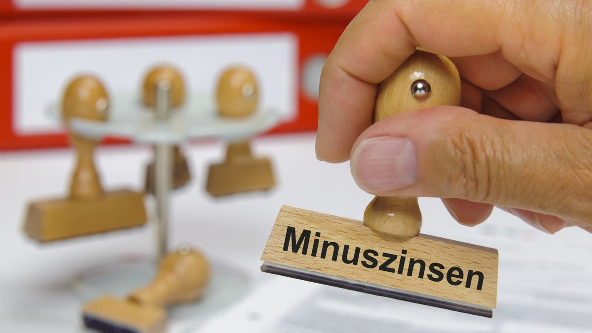 Hand hält Stempel mit der Aufschrift Minuszinsen