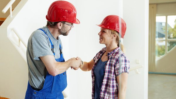 Frau und Handwerker besiegeln Auftragsvergabe mit Handshake