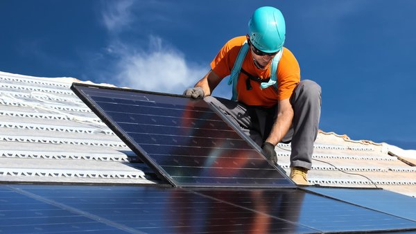 Handwerker installiert ein Solarpanel auf dem Hausdach