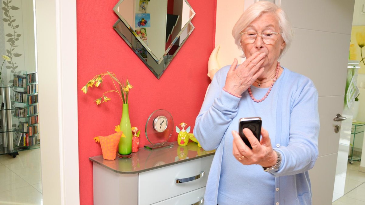 Erschreckte Senioren schaut auf ihr Smartphone