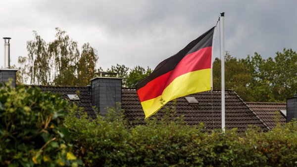 Ein genehmigter Fahnenmast im Garten mit Abstand zum Nachbarn, betrachtet vom Nachbargrundstück.