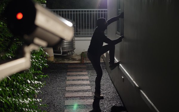 Einbrecher wird nachts von Überwachungskamera beim Einteigen in ein Haus gefilmt
