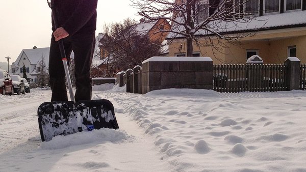 Mann beseitigt Schnee auf dem Bürgersteig mit Schneeschaufel
