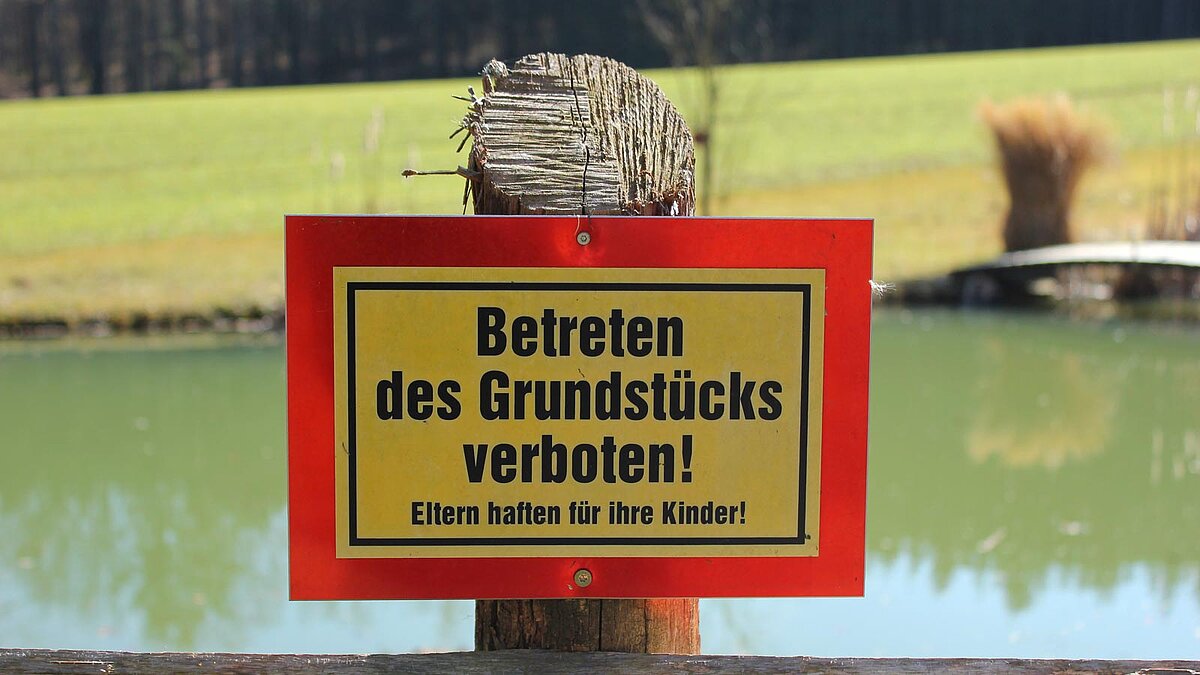 Schild "Betreten des Grundstücks verboten" vor einem Teich