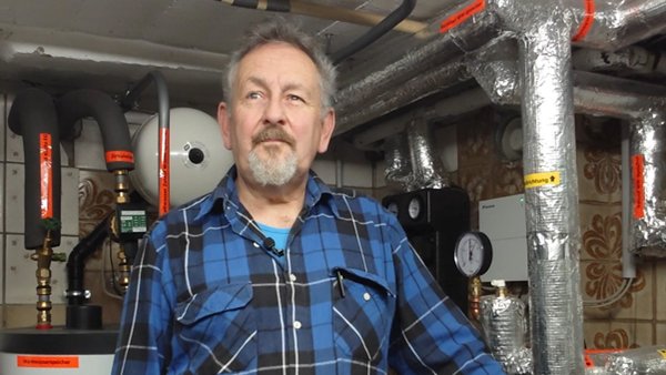 Mitglied Wilhelm Illing steht im Heizungskeller vor seiner neu eingebauten Wärmepumpe