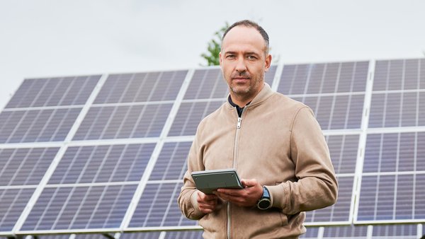 Ein Mann steht vor seiner PV-Anlage und fragt sich, ob sich die private Produktion von Solarstrom überhaupt noch lohnt.