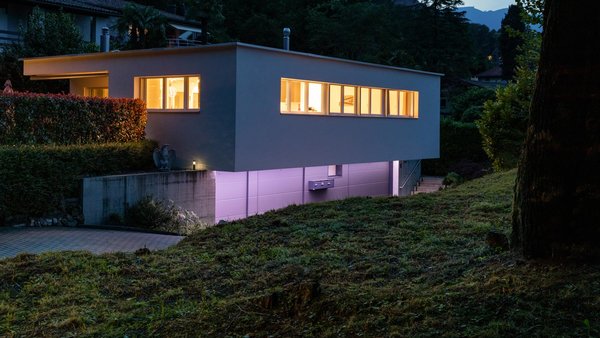 Modernes Haus in der Dämmerung mit farbiger Beluchtung der Zuwege