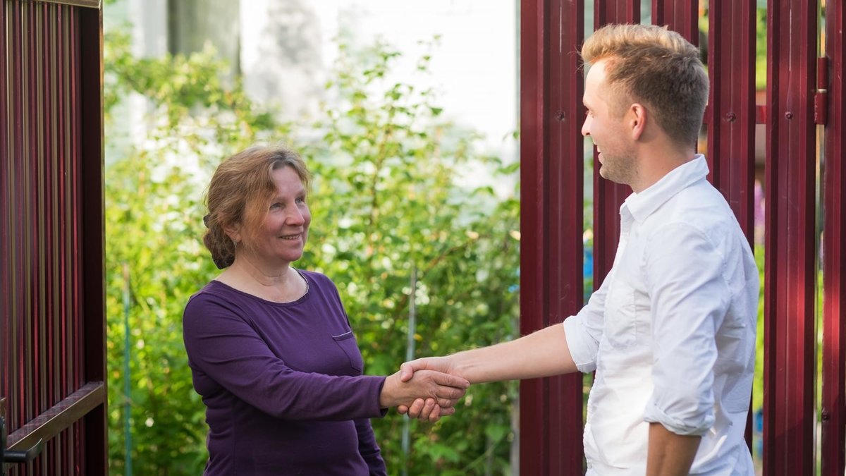 Ein Mann und eine Frau reichend sich lächelnd die Hand