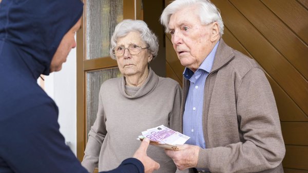 Seniorenpaar an der Haustür übergibt Bargeld an Betrüger