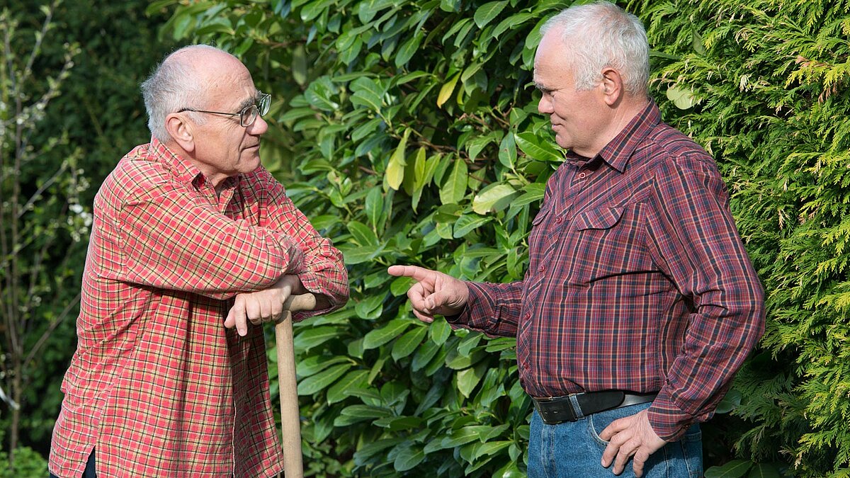 Zwei ältere Herren diskutieren im Garten