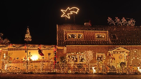 Nachtansicht von einem Haus, das komplett mit weihnachtlichen Lichterketten geschmückt ist