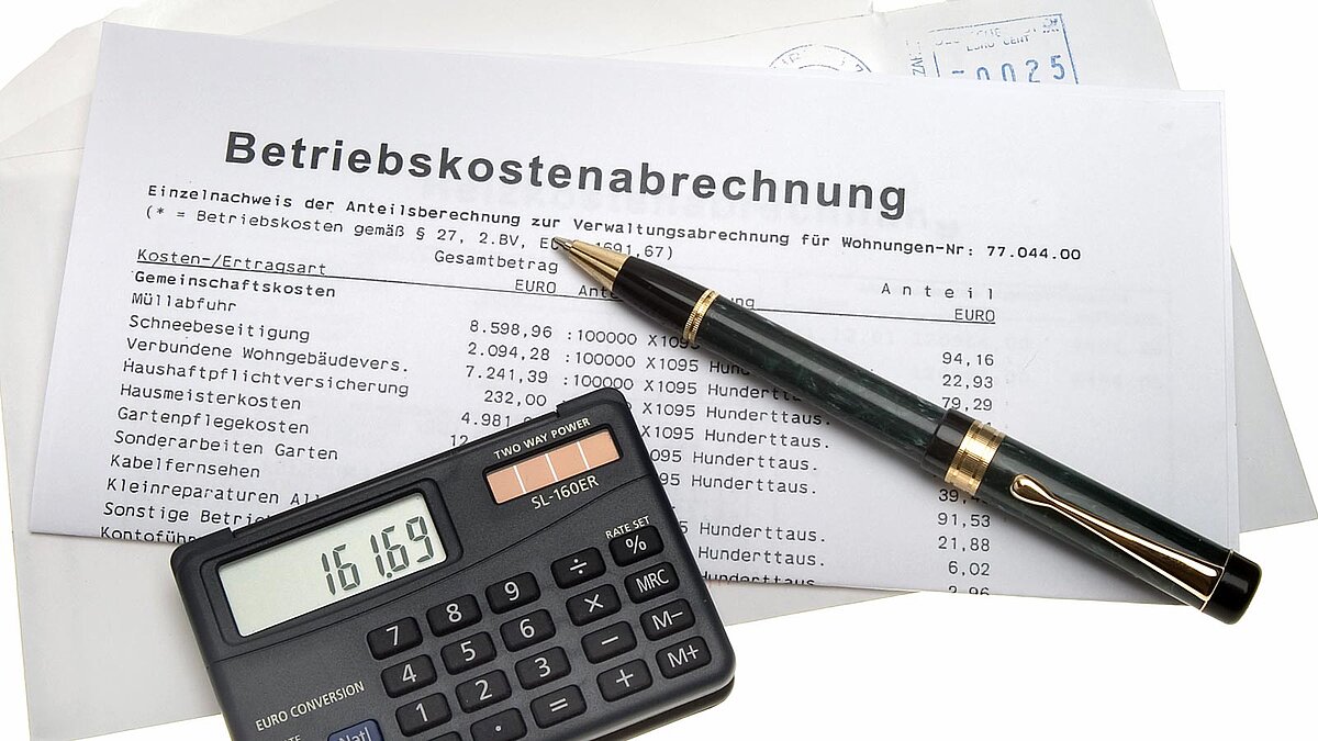 Briefumschlag, Taschenrechner und Stift liegen auf einer Betriebskostenabrechnung