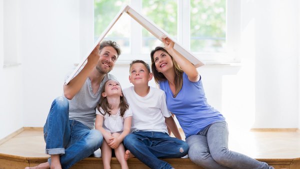 Junge Familie sitzt in einer Wohnung und träumt vom eigenen Haus