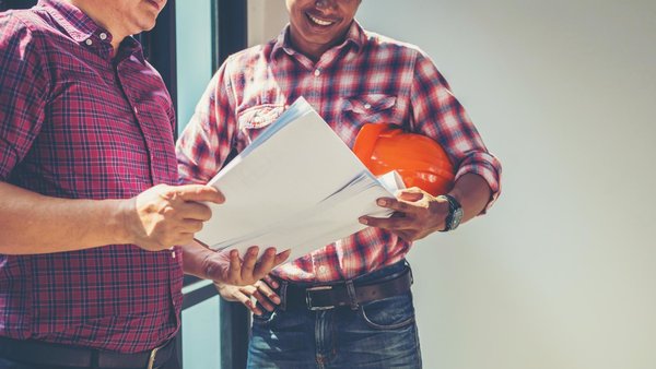 Zwei Männer beraten sich auf einer Baustelle. 