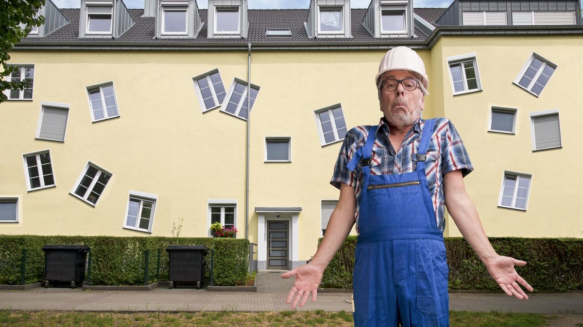 Handwerker zieht unschuldig die Schultern hoch vor verpfuschtem Haus