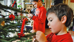 Zwei Kinder schmücken einen Christbaum