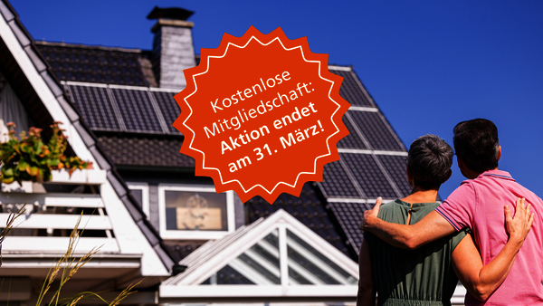 Ansicht von hinten auf ein Paar, das Arm in Arm auf sein Eigenheim schaut