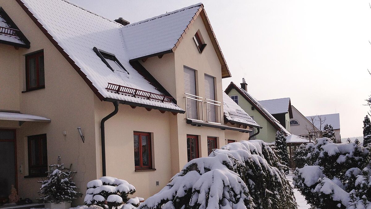 Haus mit schneebedecktem Dach und Schneefanggittern