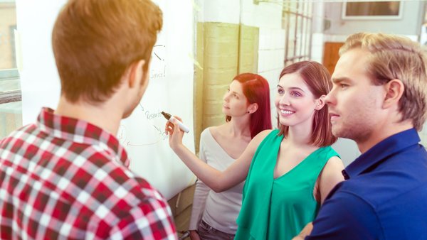 Vier junge Menschen vor einem Whiteboard