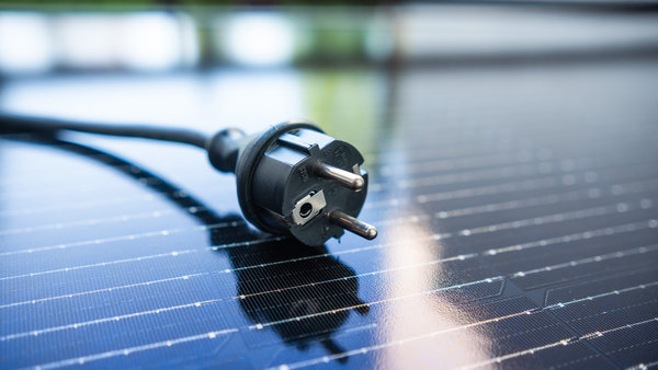 Ein Schukostecker liegt auf einem Solarpanel