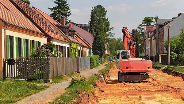 Bagger bei Straßenbauarbeiten in Wohnsiedlung