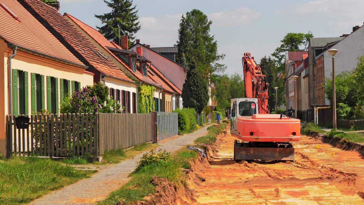 Bagger bei Straßenarbeiten in einer Siedlung