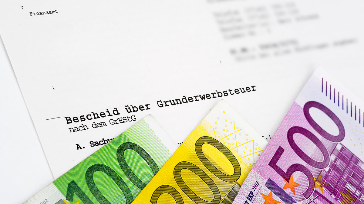 Grundsteuerbescheid vom Finanzamt mit Geldscheinen im Vordergrund.